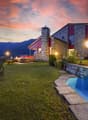 Modern house with outdoor pool, garden, mountains in background, evening lights