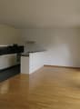 modern kitchen with white cabinets, wooden floor, black countertop, modern appliances