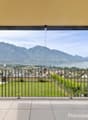 large glass walls, metal railing, tiled floor, distant view of city, mountains and lake