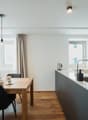 large table with chairs, modern kitchen island, white kitchen cabinets, light fixtures, window with view