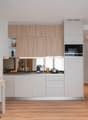 Modern kitchen with light wood cabinets, white appliances including a dishwasher, and a small dining area with a table and chair