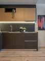 Modern kitchen with dark cabinets, wooden accents, stainless steel appliances, and a colorful abstract artwork on the wall