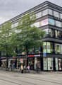 multi-story building, glass windows, parked bicycles, storefronts, pedestrians, urban setting