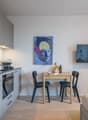 Open plan kitchen with a sink, gas stove, cabinets, microwave, and a dining table with chairs. Next to it is a bedroom with a bed.