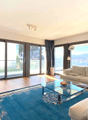 Spacious living room with large windows offering a scenic view, hardwood floors, white sofas, glass coffee table, and a TV stand.