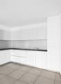 modern kitchen with white cabinets, black countertops, integrated oven, sink with faucet, tiled floor