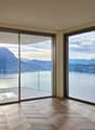 large glass windows, wooden floor, open balcony, view of lake and mountains