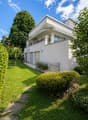 2 story house, white exterior, balcony, garage, garden, trees