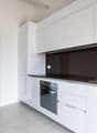 modern kitchen with white cabinets, gray tiled floor, stainless steel sink, oven, dishwasher, and a faucet