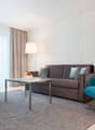 Two armchairs, coffee table, sofa, carpet, bowl of fruit, floor lamp, large window, beige curtain, wall.