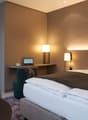 Double bed, bedspread, pillows, lamps, desk, laptop, chair, table, refrigerator, microwave, kettle, kitchen cabinet, grey walls