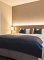comfortable bed, decorative lamps, wooden floor, large mirror in bathroom, bathtub and sink