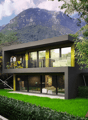 Modern two-story house with large windows, black exterior, surrounded by lush greenery and mountains in the background. The house has a balcony or terrace overlooking the scenic landscape.