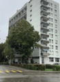 High-rise building, white exterior, multiple balconies, trees, shrubs, street