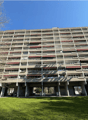 multi-story building, concrete structure, multiple balconies, green lawn in front