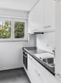 modern kitchen with white cabinets, black countertops, stainless steel sink, electric stove, oven, dishwasher, window