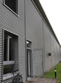 Metal cladding, glass windows, open door, bicycles, concrete path, metal pole, grassy area