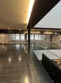 large shopping mall, empty, tiled floor, high ceiling, shops, sign for MANOR, light and glass railings
