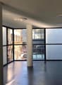 Large room, high windows, modern design, central pillar, grey floor, glass windows, reflective surfaces