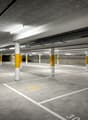 Concrete floor, yellow and white columns, designated parking spaces, disabled parking symbol, white lines marking parking spots, fluorescent lighting.