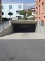 Underground parking lot with a ramp, metal railings, and a yellow car parked outside