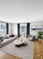 modern living room with gray couch, coffee table, armchair, TV, wooden floor, sliding glass doors to balcony