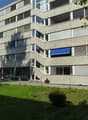 Modern apartment building, many windows, terrace, outdoor area, parking, entrance area, bicycles parked