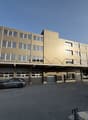 4 story building, brown exterior, multiple windows, garage, car parked in front