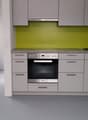 Modern kitchen with gray cabinets, green backsplash, built-in oven and dishwasher, and a sink with faucet