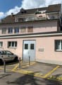apartment building, multiple floors, 2 cars parked, grey metal poles in parking lot