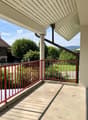 concrete floor, red metal railing, view of the yard and mountain
