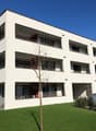 modern white apartment building with balconies, large windows, flat roof, spacious green lawn