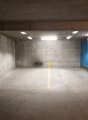 concrete walls, gray floor, yellow marking lines, blue plastic barriers, ceiling lights