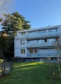 white house, several balconies, 3 floors, large windows, garden, shrubs, green grass
