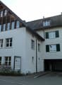 3 story house, white walls, wooden roof, multiple windows, garage