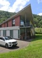 modern house, red wall, gray roof, glass windows, garage, large driveway, green grass, white car