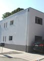 2 story building, white facade, 6 windows, 2 cars parked in front and garage