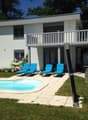 modern white house, with balcony, 3 lounge chairs, swimming pool, grass, flower beds