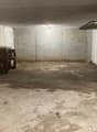 Empty parking area with concrete floor, brick wall, single car entrance, metal door, small window, car in front of garage.