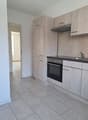 modern kitchen with white tiled floor, wooden cabinets, stainless steel appliances, and a sink with a faucet