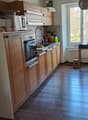 kitchen with wooden cabinets, oven, sink, window, wooden floor