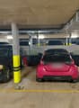 underground parking lot with multiple cars parked, yellow and white markings, yellow and black poles