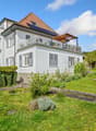 2 story house, white exterior, brown roof, balcony, solar panels, garden, bench
