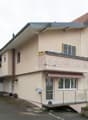 2-story house, beige exterior, brick base, staircase, balcony, awning, large driveway, plants, fence, parked car