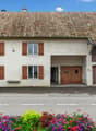 white house, brown tiled roof, brown wooden shutters, two garages, entrance