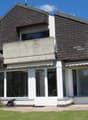 Modern white house, brown roof, terrace, garden, glass windows, shrubs