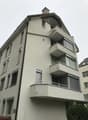 4 story building, white exterior, multiple balconies, windows with shutters