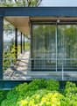 Modern design, large windows, metal railing, wooden floor, elevated position, greenery, and view of the surrounding area