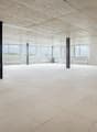 large room, white tile flooring, concrete ceiling, exposed beams, large windows