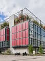 modern office building with red facades, glass windows, green roof, and modern architectural design